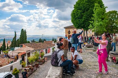 Varios turistas toman fotos desde el mirador de San Nicolás, desde donde hay una de las mejores vistas de la Alhambra de Granada.