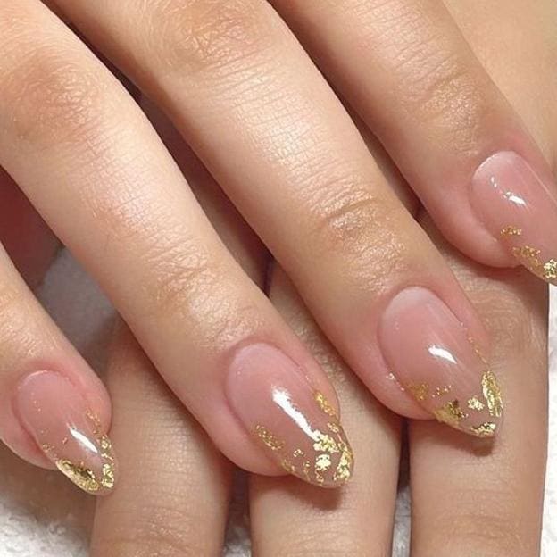 Manicura con detalles dorados brillantes.