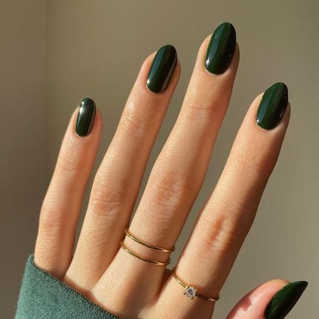 Manicura con barniz verde oscuro.