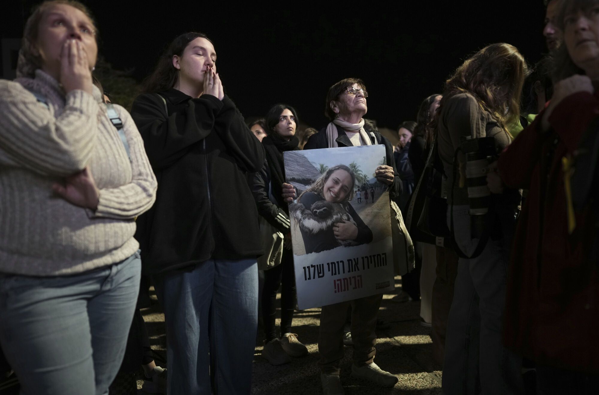 Relatives and friends of people killed and abducted by Hamas and taken into Gaza, one of them holding a photograph of Romi Gonen, react to the news during a gather in Tel Aviv, Israel on Sunday, Jan. 19, 2025. (AP Photo/Oded Balilty)