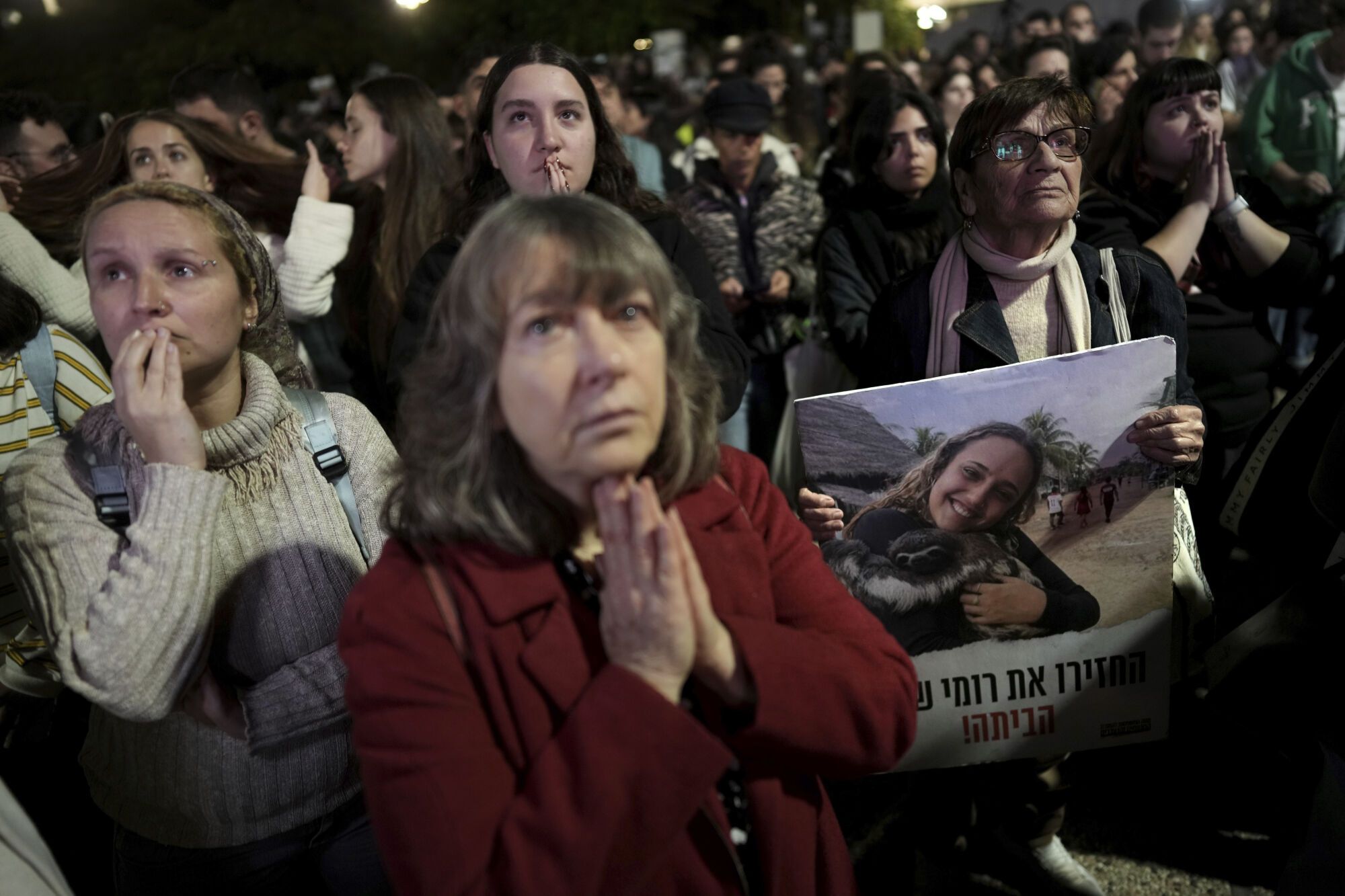 Relatives and friends of people killed and abducted by Hamas and taken into Gaza, one of them holding a photograph of Romi Gonen, react to the news during a gather in Tel Aviv, Israel on Sunday, Jan. 19, 2025. (AP Photo/Oded Balilty)