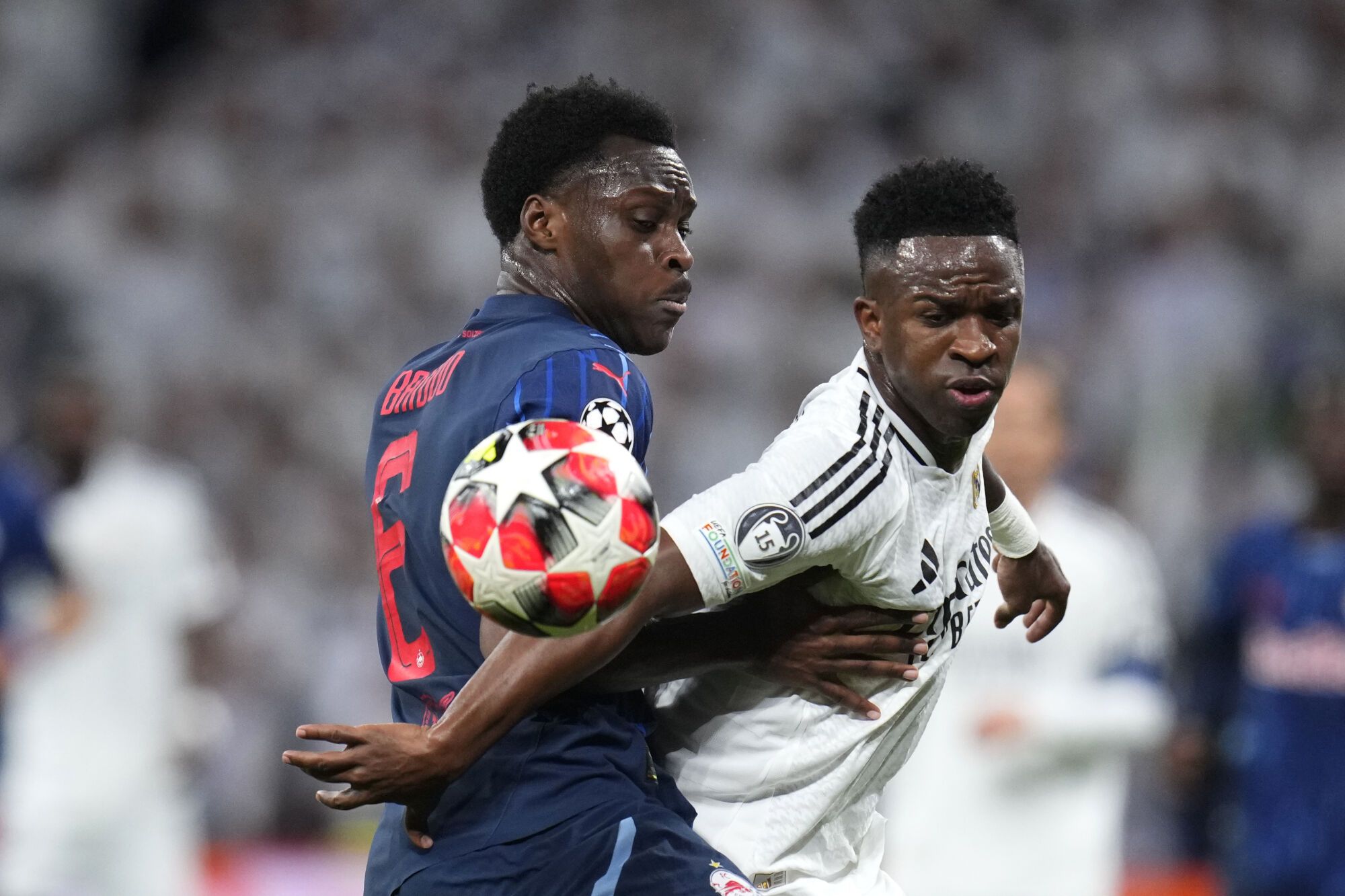 Samson Baidoo del Salzburgo, izquierda, y Vinicius Junior del Real Madrid compiten por el balón durante el partido de fútbol de la fase inaugural de la Liga de Campeones entre el Real Madrid y el FC Salzburg en el estadio Santiago Bernabeu de Madrid, el miércoles 22 de enero de 2025. (Foto AP/Manu Fernández)