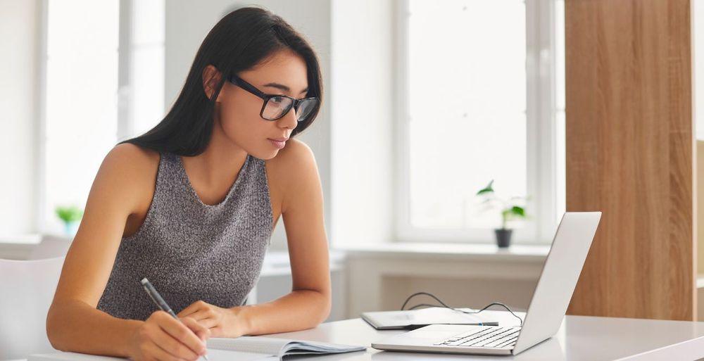 Una chica mirando la pantalla de una computadora portátil mientras escribe