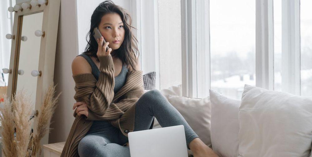 Una chica habla cómodamente por un teléfono móvil y utiliza una computadora