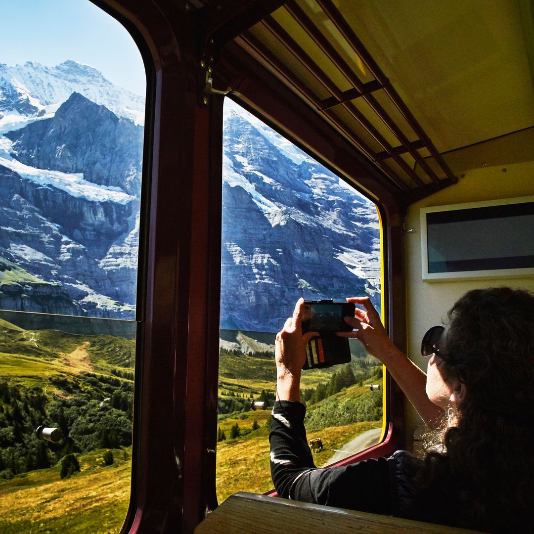 Mujer viajando en tren por Europa entre paisajes montañosos