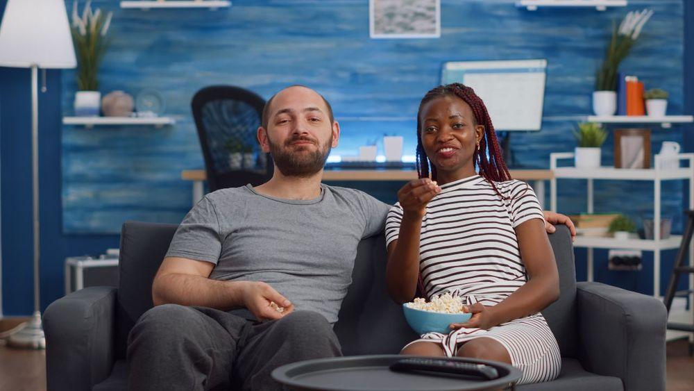 Feliz pareja sentada en el sofá viendo la televisión