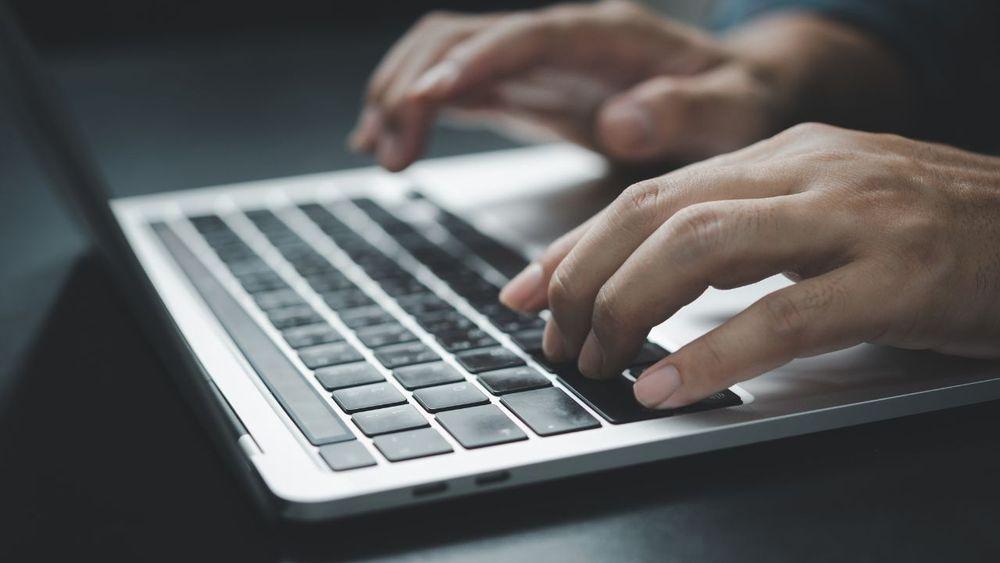 Escribiendo en la computadora portátil con las manos