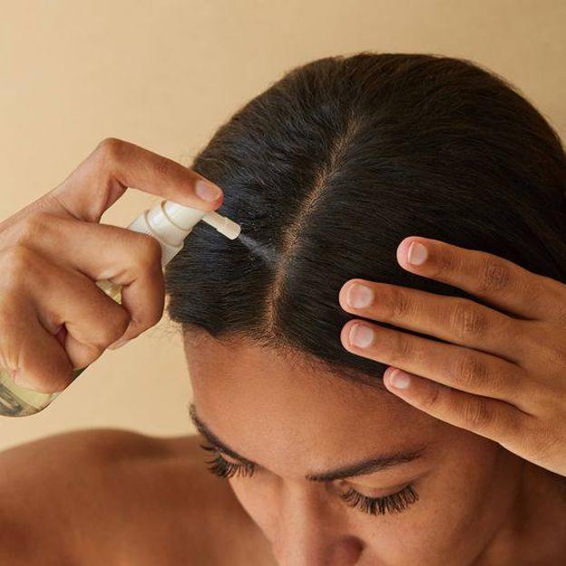 Mujer aplicando agua de romero al cabello