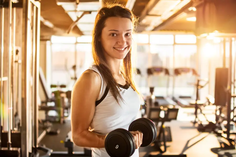 Chica haciendo pesas en el gimnasio.