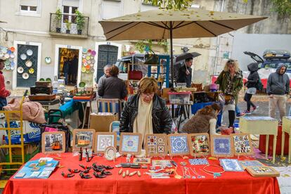 Una mujer con un poste de baldosas con la popular feria da Ladra, en Lisboa.