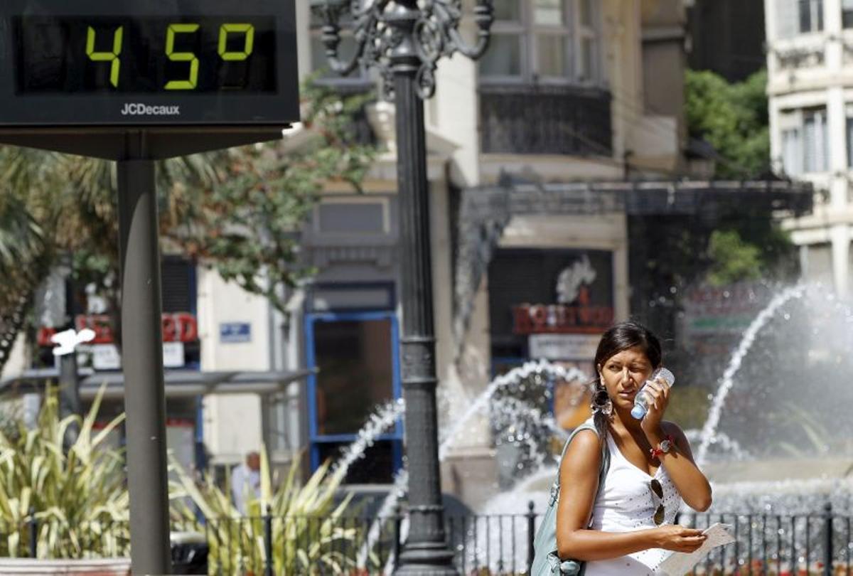 Una mujer pasa ante un termómetro que marca 45 grados.