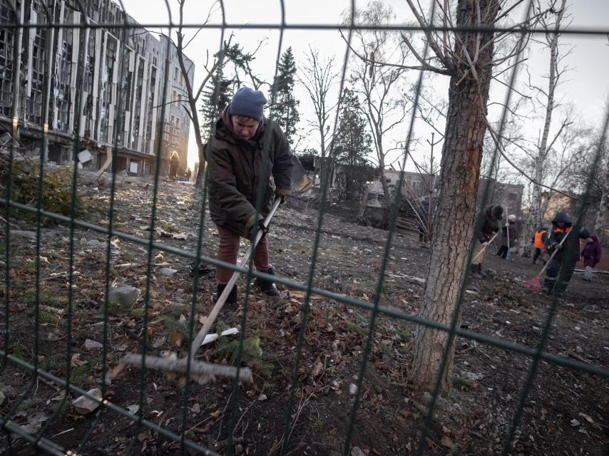 Los vecinos de Izyum intentan limpiar los cristales y los restos de escombros de la vecindad del Ayuntamiento de Izyum, después de que Rusia lo bombardea con un misil balístico.