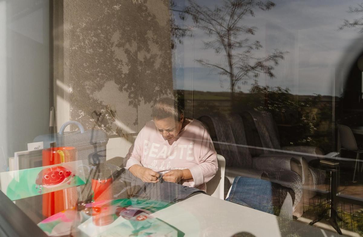 Alicia cose en el escritorio de su piso, en el 'cohousing senior' de Trabensol en Torremocha del Jarama, Madrid.