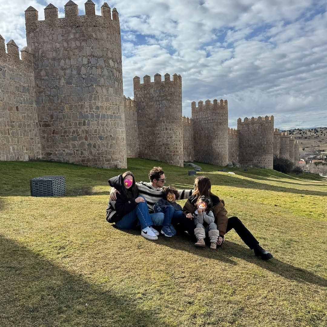 La familia completa posa al lado de la pared.