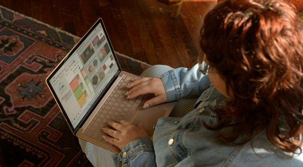 Una mujer escribiendo con laptop en casa