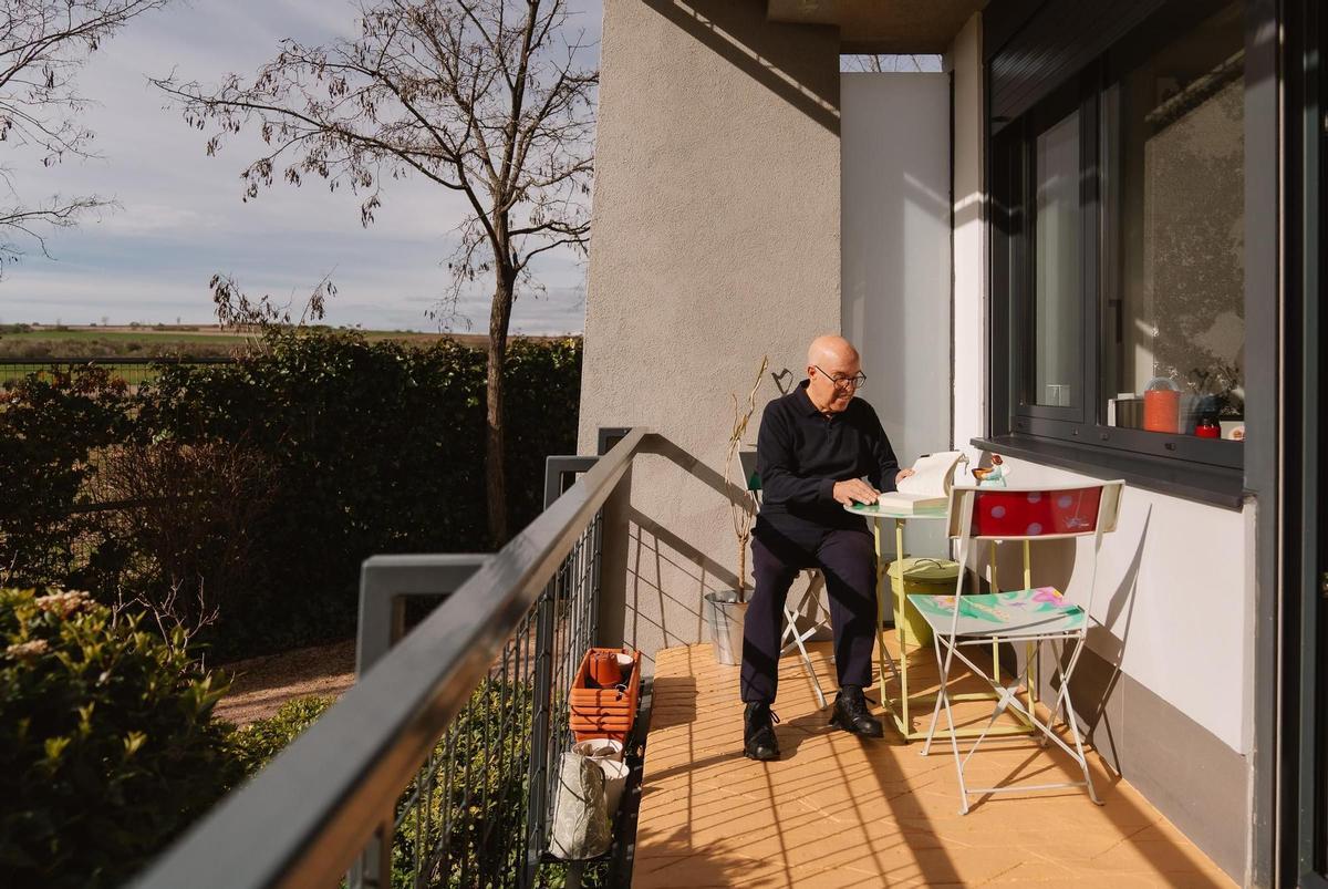 Pepe lee en la terraza de su piso, en el 'cohousing senior' de Trabensol en Torremocha del Jarama, Madrid.