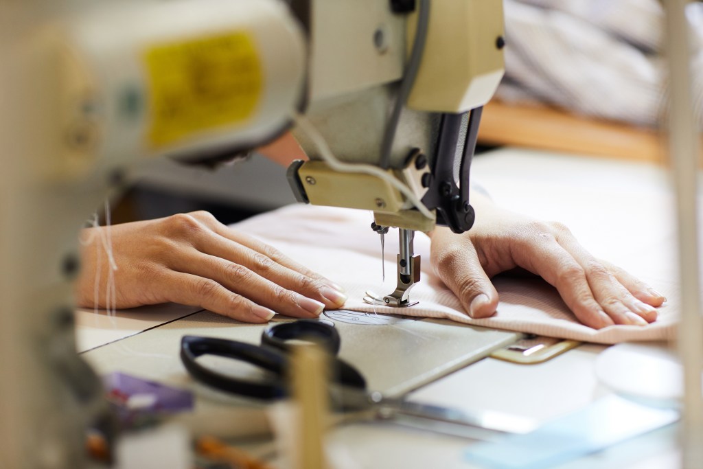 Mujer cosiendo con máquina de coser - Imagen: iStock