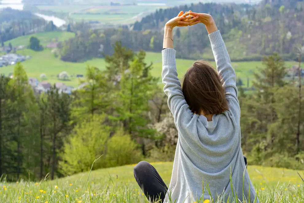 Mujer relajada en medio de la naturaleza sentada en el campo