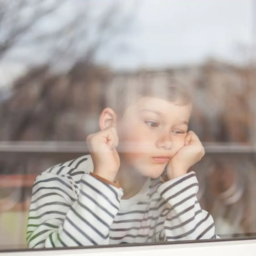 Niño aburrido mirando por la ventana