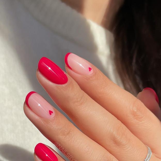 Uñas de color rojo cereza con manicura francesa y dibujos de corazón