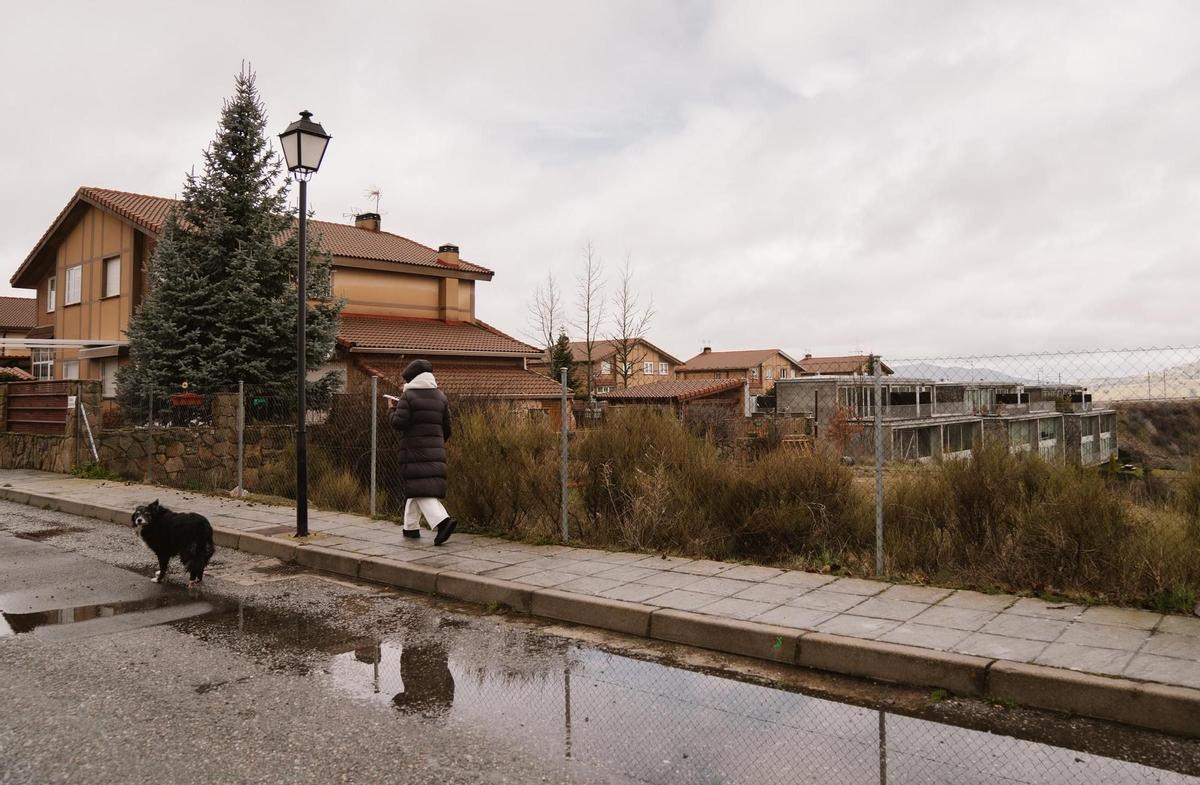 Una mujer pasea cerca de la urbanización Bellavista, la zona de La Estación de El Espinar donde podría llegar el agua de colapsar la presa.