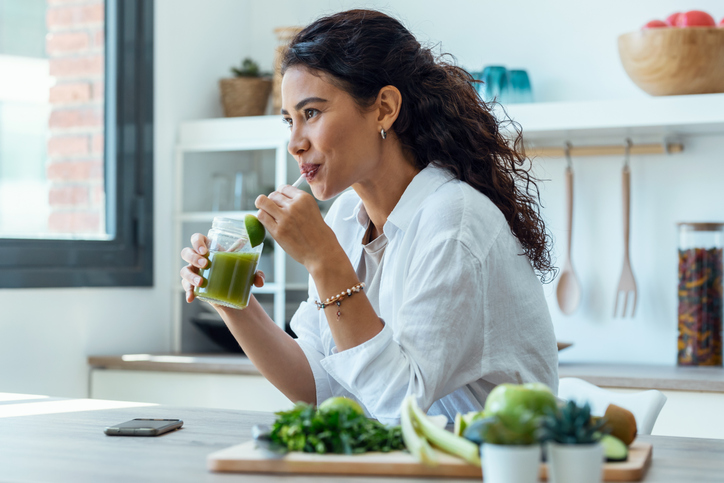 Mujer bebe verduras con vitamina K 