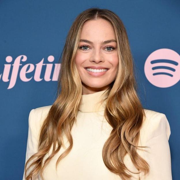 Margot Robbie con una moneda plateada rubia en cabello castaño