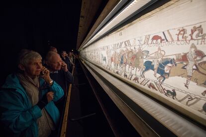 Varios visitantes observan el tapiz de Bayeux.