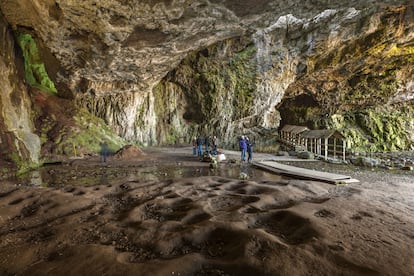 Varios turistas exploran el interior de la cueva de Smoo.