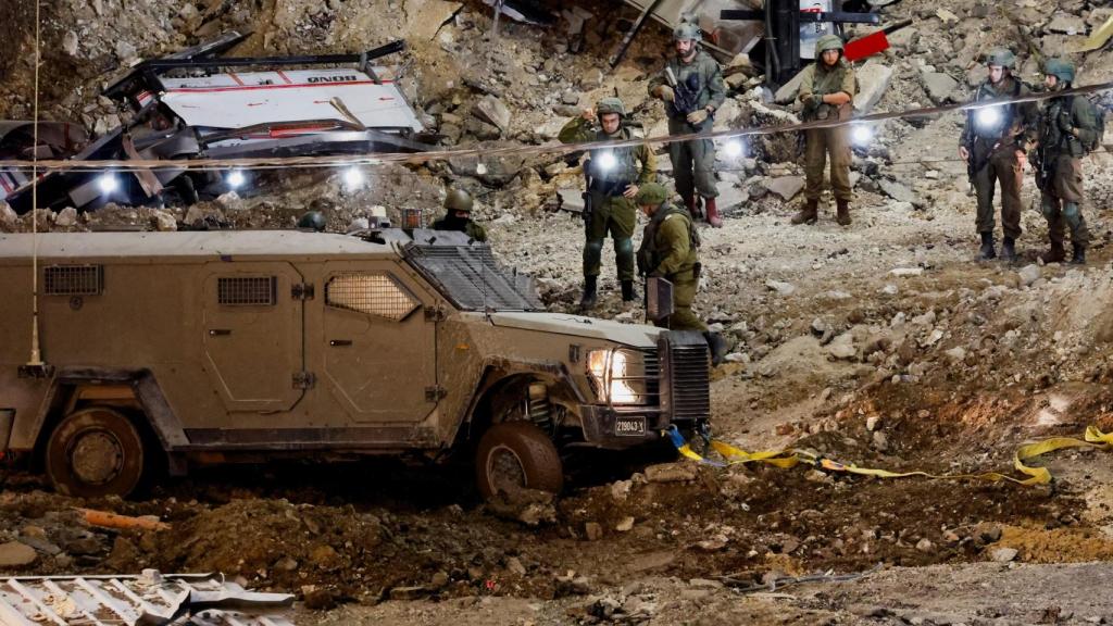 Los miembros del ejército israelí permanecen al lado de un vehículo militar mientras una incursión israelí continúa en Jenin, en Cisjordania.