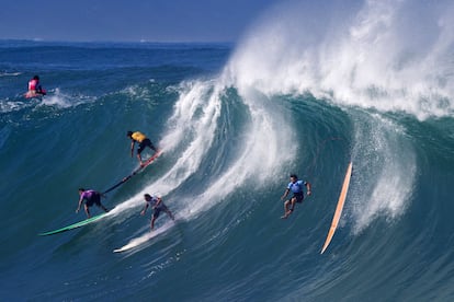 Varios surfistas toman una ola en una playa en el norte de Oahu, en Hawai.