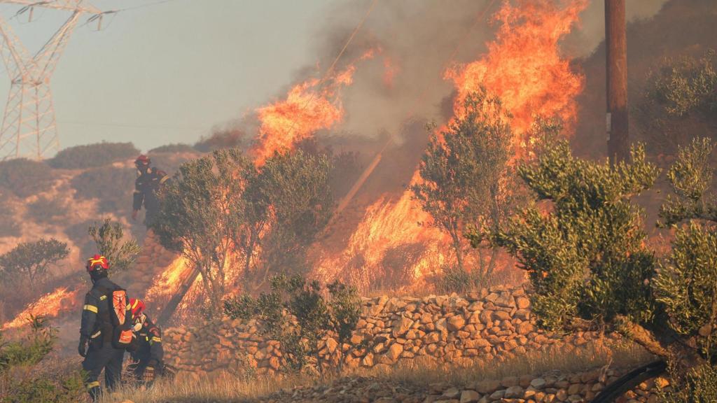 Los bomberos permanecen al lado de las llamas mientras un fuego forestal quema cerca de Irera, en la isla de Creta, Grecia, el 3 de julio de 2025.