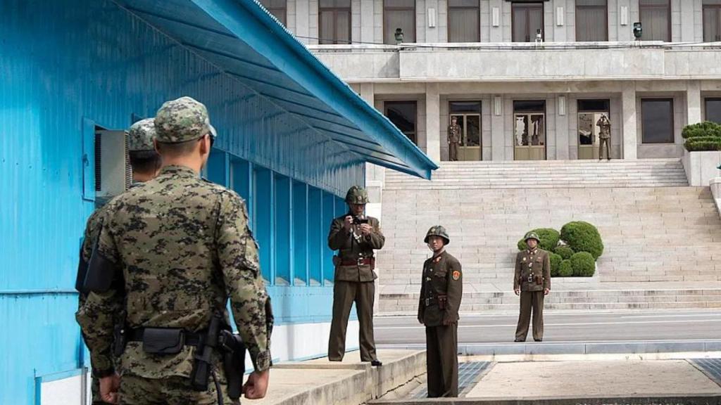 Los soldados norcoreanos permanecen en el lado norcoreano, uno de ellos usando una cámara, mientras que los soldados surcoreanos los enfrentan en la frontera del área desmilitarizada (DMZ), en Panmunjom.