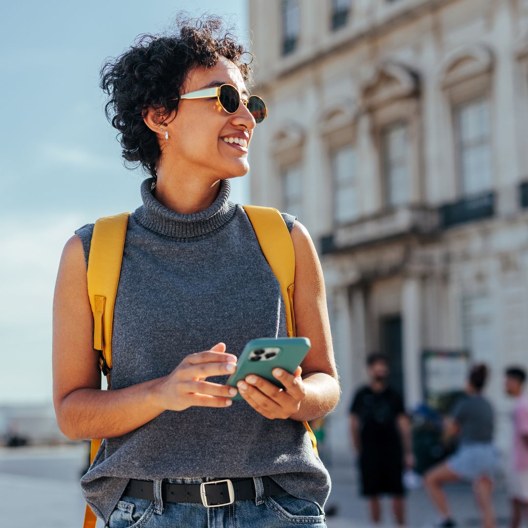 Une jeune femme explore une ville avec son téléphone portable à la main