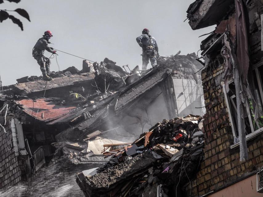Los rescatistas y bomberos trabajan en uno de los edificios residenciales bombardeados por Rusia esta mañana, en Kiev, donde al menos 14 civiles han muerto.