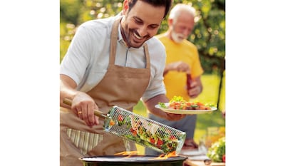 Vegetales de cocina a la parrilla con una cesta de acero inoxidable.