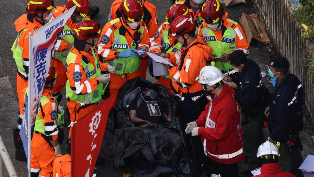 . El personal médico registra los detalles de un cuerpo recuperado del complejo residencial Wang Fuk Court.