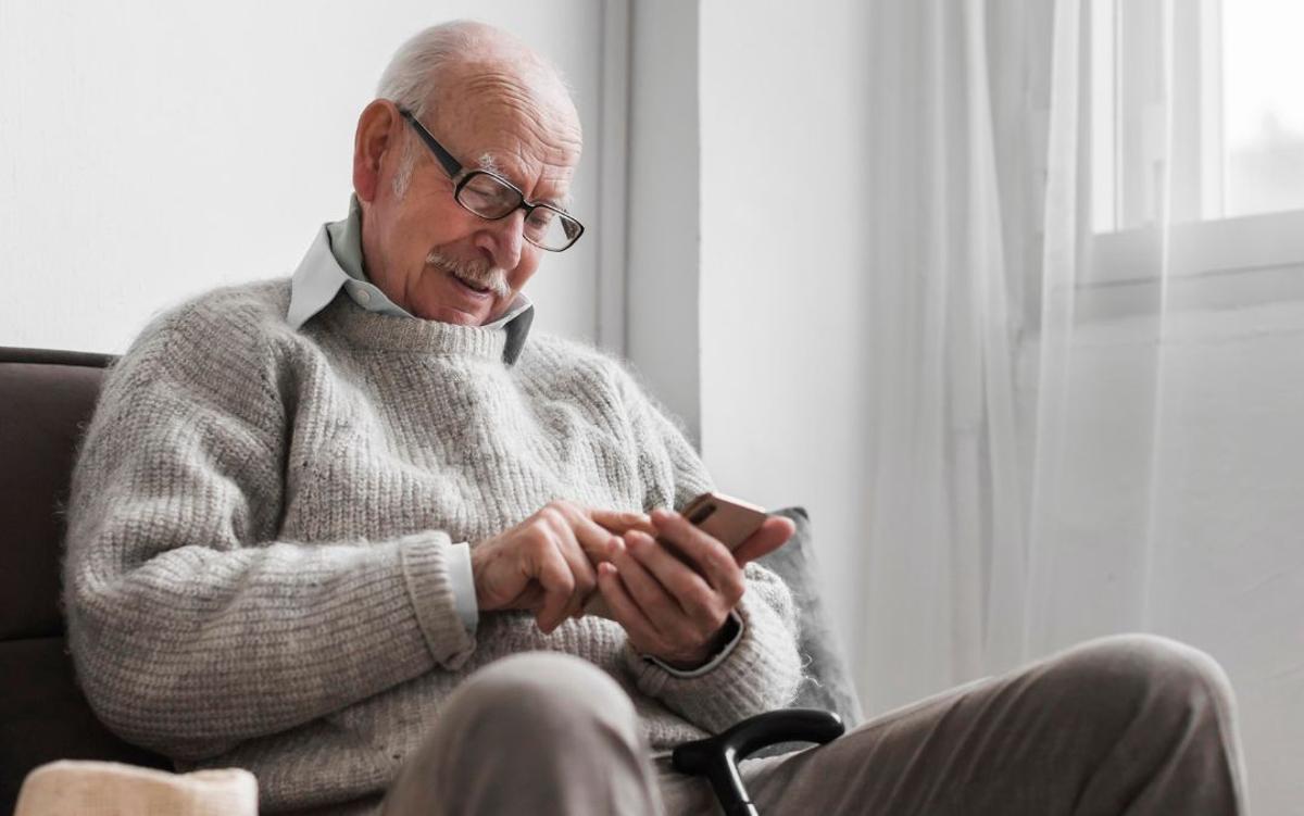 Persona mayor usando su teléfono inteligente.