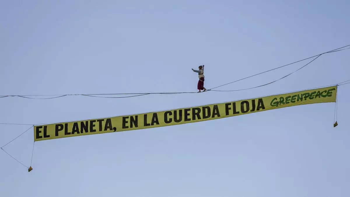 Un activista de Greenpeace camina sobre una cuerda de 30 metros de altura en Madrid