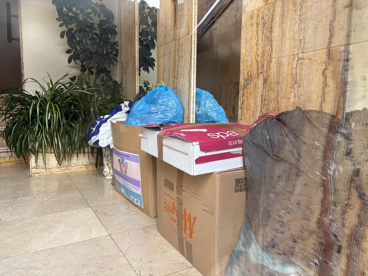 Bolsas y cajas acumuladas en un portal de la calle Mayor para donar.
