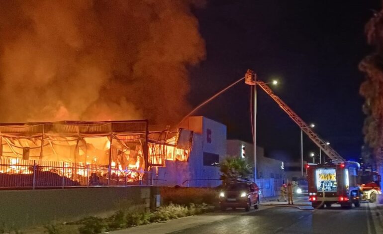Bomberos trabajan en la extinción de un incendio industrial con llamas muy altas en una nave de Elda (Alicante)