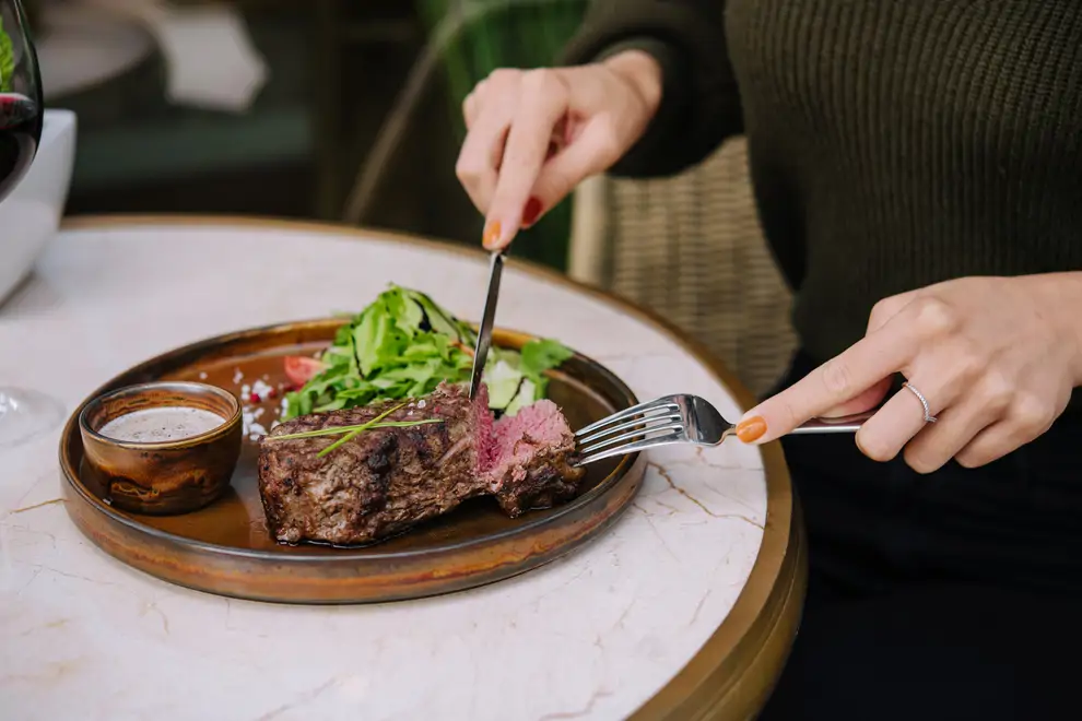 Mujer comiendo un plato de carne
