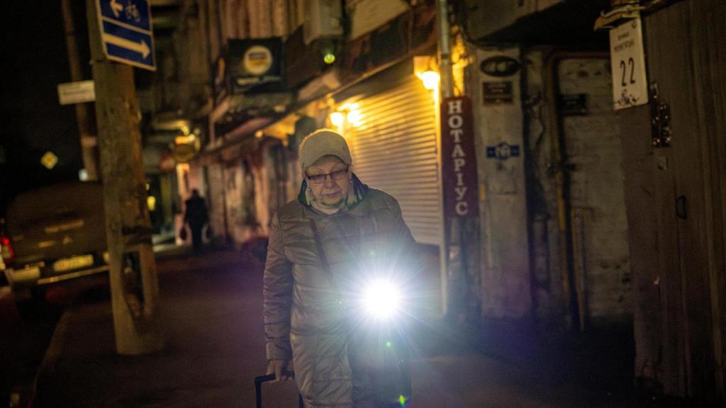 Una mujer camina con una linterna por las calles de Kyiv, completamente a oscuras.