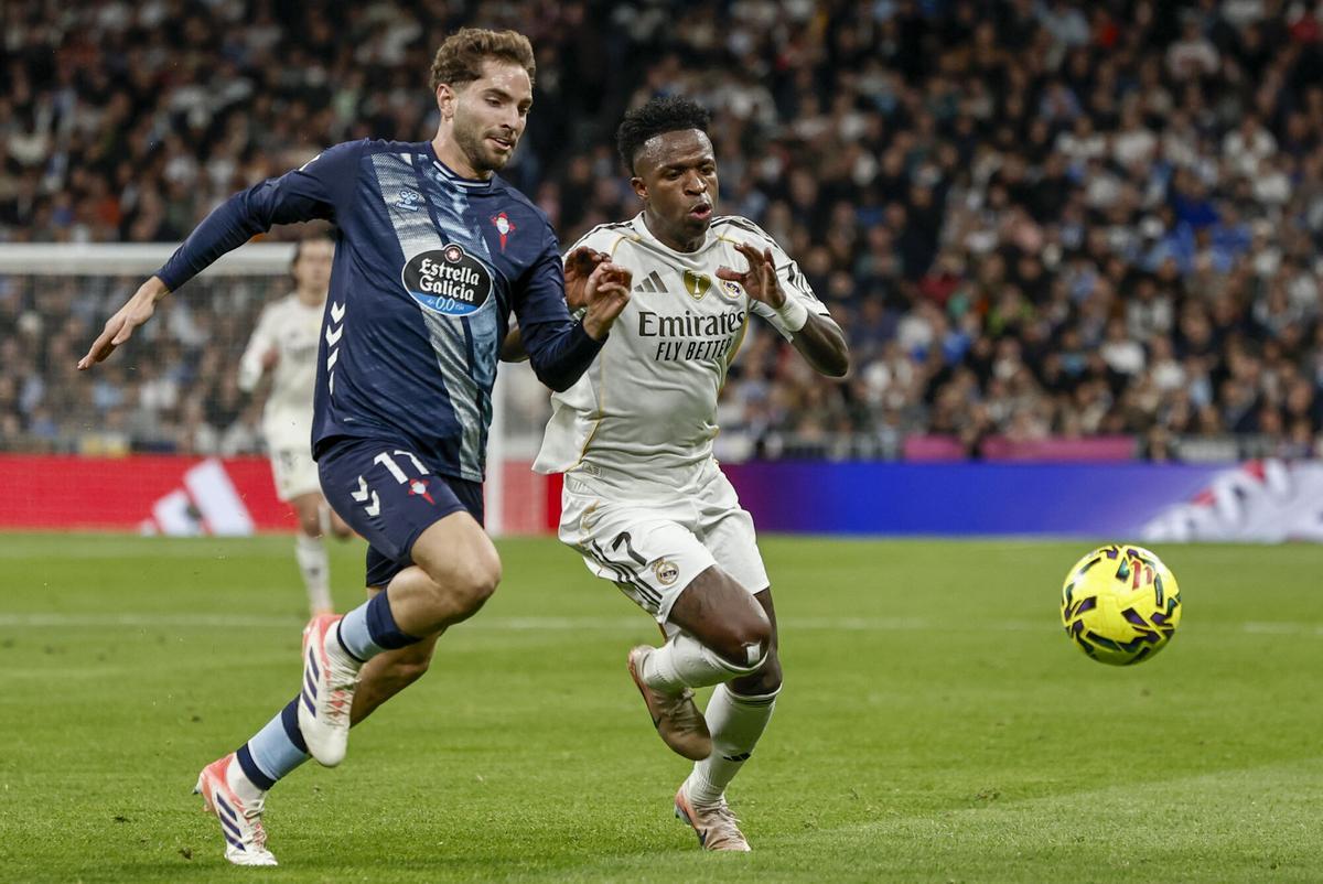 MADRID, 12/07/2025.- El defensor del Celta Javi Rueda (i) lucha por el balón con Vinicius Junior, del Real Madrid, durante el partido de fútbol de la Liga entre el Real Madrid y el Celta de Vigo este domingo en el estadio Santiago Bernabéu. EFE/Sergio Pérez