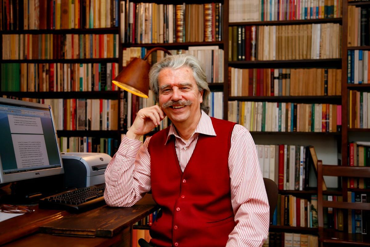 Lluís Permanyer, en su casa, junto a la mesa de su despacho y su gigante biblioteca personal.