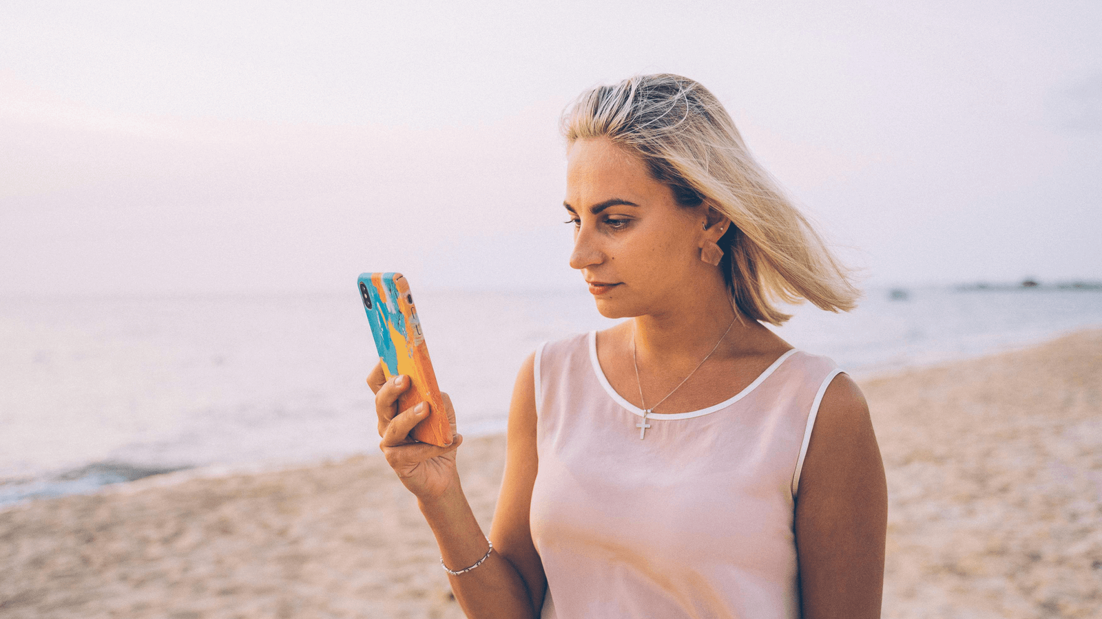 Una niña usa el teléfono móvil en la playa.