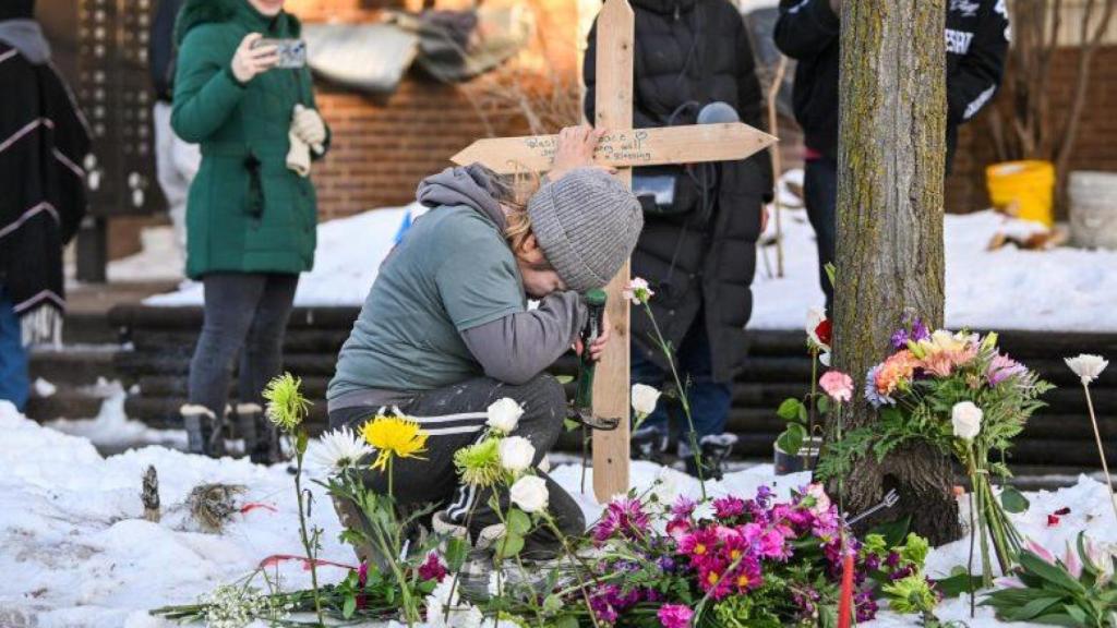 Una mujer reza en un monumento conmemorativo en el lugar donde Renee Nicole Good fue asesinada a tiros en Minneapolis.
