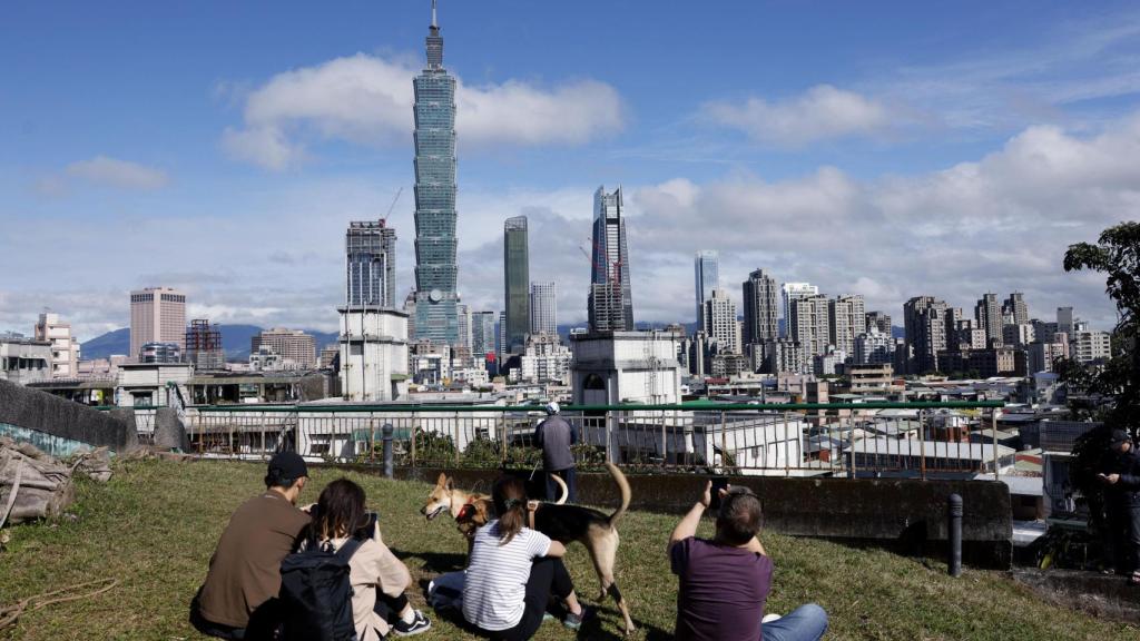 Varias personas observan desde lejos cómo Alex Honnold asciende al rascacielos taiwanés Taipei 101.