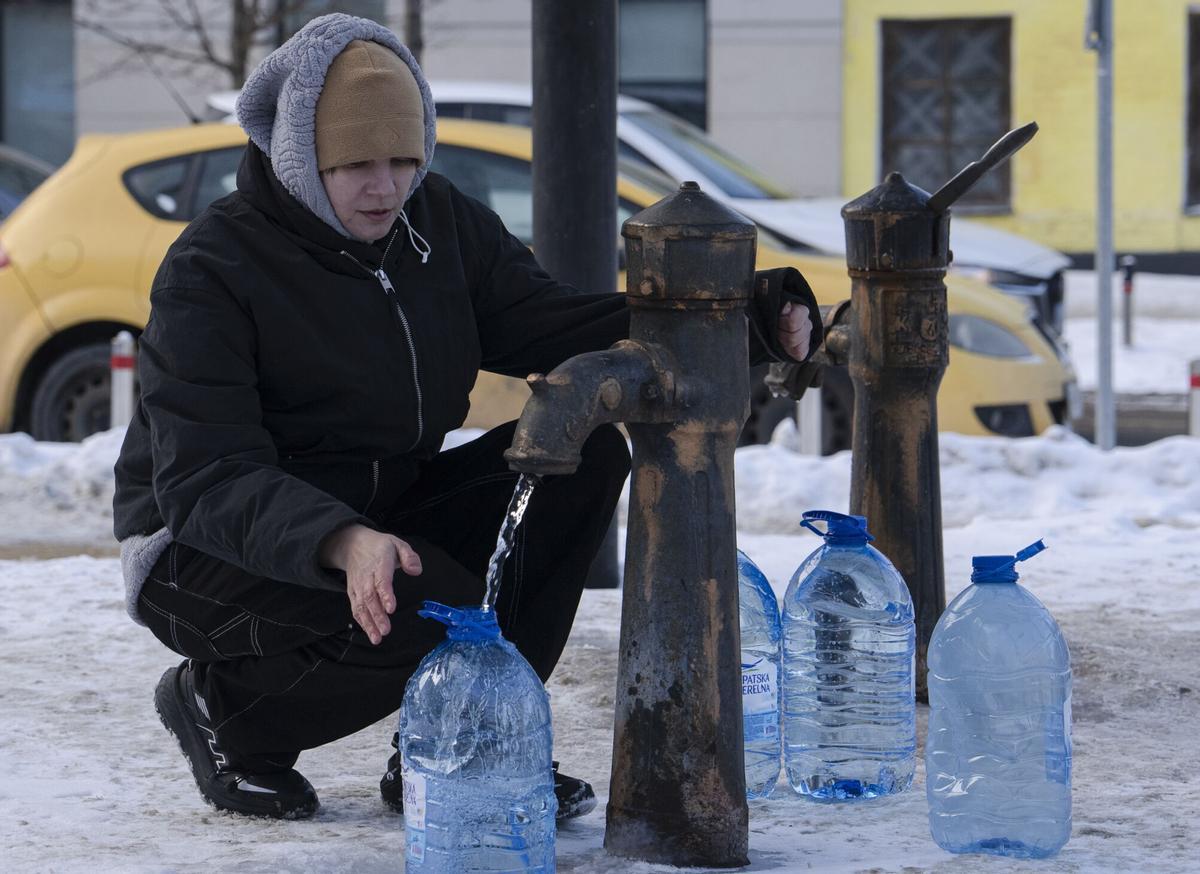Una mujer llena jarras de agua en una fuente pública en Kyiv.