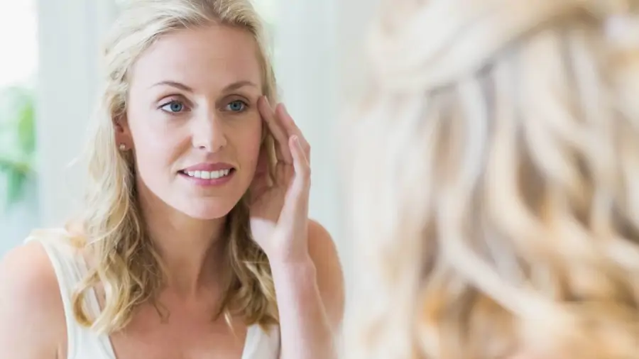 mujer mirando su piel en el espejo